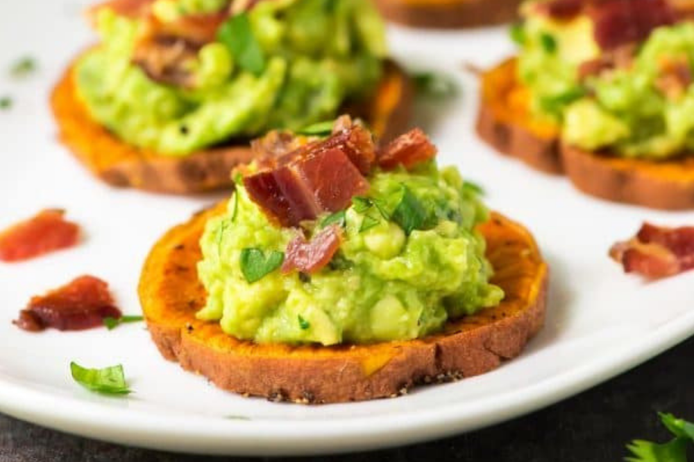 Sliced and baked sweet potato topped with bacon and avocado