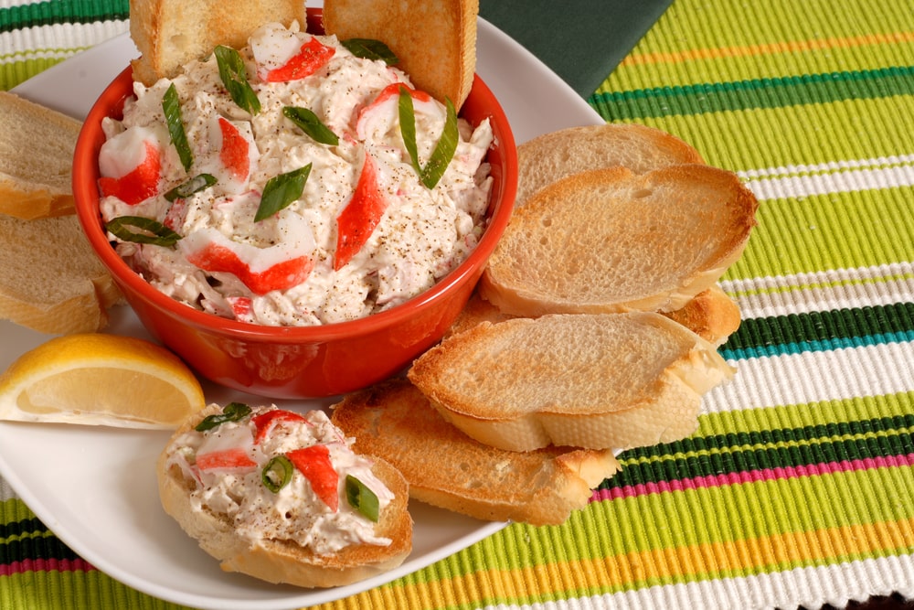Spicy crab dip surrounded by toasted bread and lemon 