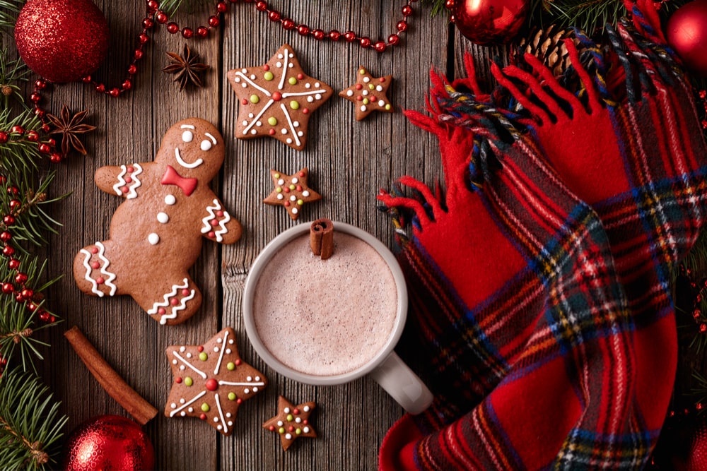 Festive gingerbread man cookie with winter scarf and hot chocolate
